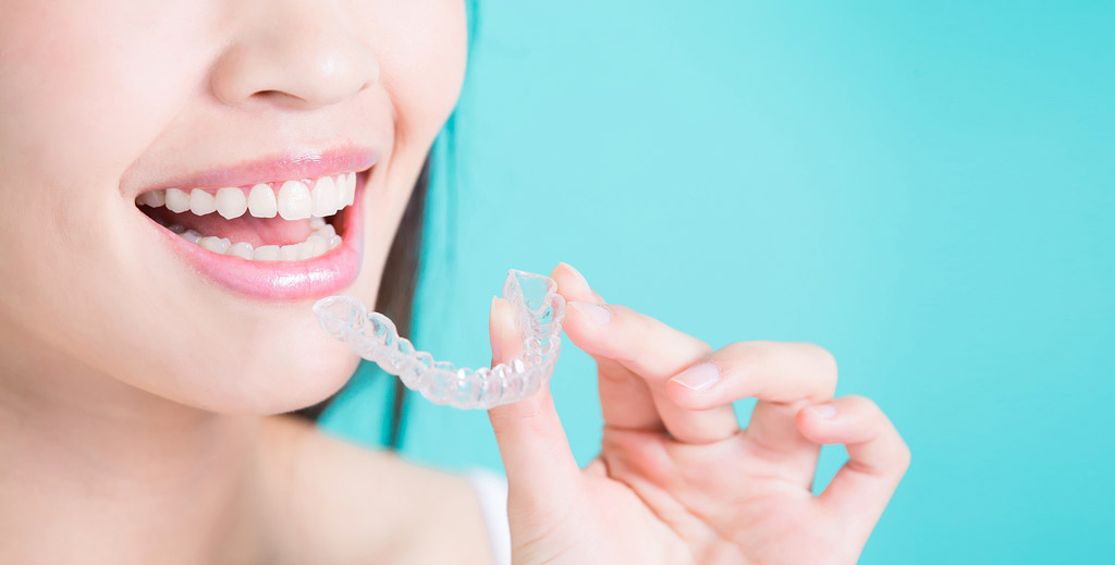 close up of a female with perfect white teeth holding invisalign